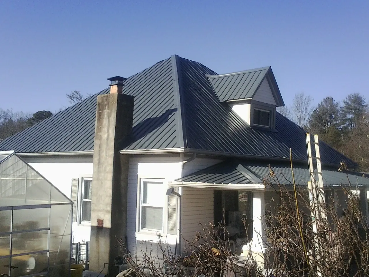 Dark blue standing seam metal roof on a white farmhouse with dormer — Slate & Tile Roof Repair by Roofing Brothers in Wappingers Falls