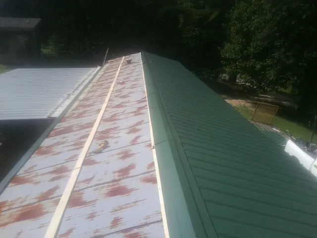 Old rusted panels beside newly installed green metal roofing — Wind Damage Roof Repair by Roofing Brothers in Wappingers Falls