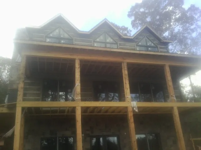 Dormers and porch framing on a large log home under construction — Roof Coating work by our crew in Wappingers Falls