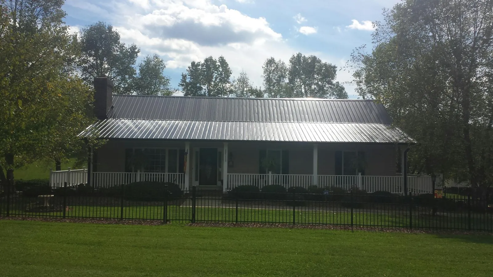 Gray metal roof on a brick ranch with a full width front porch — Gutter Guard Installation work by our crew in Wappingers Falls