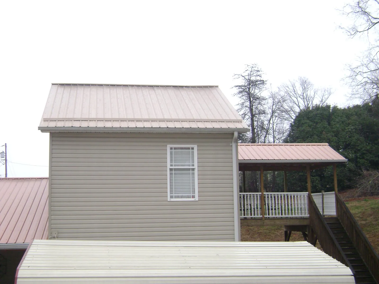 Tan metal roofs on a two story addition and attached porch, from a Roof Replacement job in Wappingers Falls