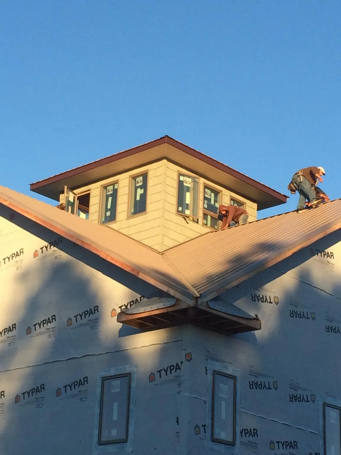 Roofers working around a rooftop cupola on a new metal roof at sunset — Roof Waterproofing in Wappingers Falls by Roofing Brothers